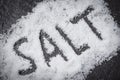 Heap of white salt dark background with text SALT Royalty Free Stock Photo