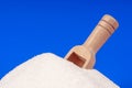 Heap of white sugar with a wooden spoon on a blue background Royalty Free Stock Photo