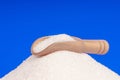 Heap of white sugar with a wooden spoon on a blue background Royalty Free Stock Photo