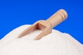 Heap of white sugar with a wooden spoon on a blue background Royalty Free Stock Photo