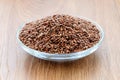 Heap of whole flax seeds in a glass saucer on a wooden table. Healthy food for lower cholesterol and preventing heart diseases