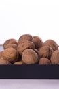 Heap of whole walnuts in shell on plate, side view on white background. Healthy nuts and seeds background. Royalty Free Stock Photo