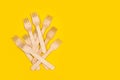 A heap of wooden forks on a yellow background