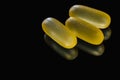 Heap of yellow capsule pills tablets medicine lying isolated on black background extreme close-up. Royalty Free Stock Photo