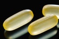 Heap of yellow capsule pills tablets medicine lying isolated on black background extreme close-up. Royalty Free Stock Photo