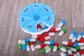 a Heaps of colorful capsules lie on a wooden table with a round pill dispenser for a week Royalty Free Stock Photo