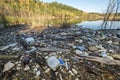 Heaps of construction waste, household waste, foam and plastic bottles on the shore of a forest lake, environmental pollution