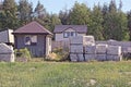 heaps of white bricks on pallets for construction near a small gray house with a window