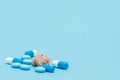 Hearing aid and blue pills on blue background. Medical, pharmacy and healthcare concept. Copy space. Empty place for text or logo