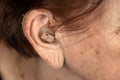 Hearing aid device in senior woman ear - closeup photo. Royalty Free Stock Photo