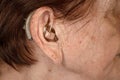 Hearing aid device in senior woman ear - closeup photo. Royalty Free Stock Photo