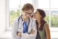 Funny teenage girl having fun looking through otoscope at ear of friendly female doctor. Royalty Free Stock Photo