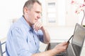 Hearing impaired man working with laptop and mobile phone