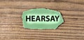 HEARSAY - word on green torn piece of paper on old brown board background