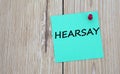 HEARSAY - word written on a green sheet for notes, which is pinned to a light wooden board