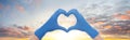 Heart against sky clouds background. Heart builded from hands in doctor gloves Royalty Free Stock Photo