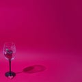 Heart as an expression of love in a wine glass on a red background with a shadow of glass. Minimalistic romantic scene