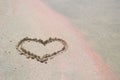 The heart as a symbol of love is painted on the white and pink sand. Royalty Free Stock Photo