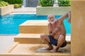 Heart attack concept. Senior man suffering from chest pain on Outdoor rain shower by swimming pool Royalty Free Stock Photo