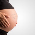 Heart on the bare swollen belly of a pregnant woman