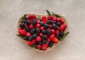 Heart of berries. Fresh ripe raspberries, blackberries, strawberries and blueberries on beige background in basket Royalty Free Stock Photo