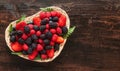 Heart of berries. Fresh ripe raspberries, blackberries, strawberries and blueberries on a dark wooden background in basket. Berry Royalty Free Stock Photo