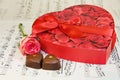 Heart box of chocolates with rose over music notes