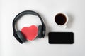 Heart box with stereo headphones, smartphone and cup of tea on a white background. Top view copy space