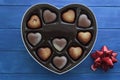 Heart box of valentines chocolate and red bow on blue wooden table