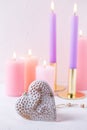 Heart and burning candles in pastel colors on white textured background. Royalty Free Stock Photo