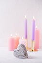 Heart and burning candles in pastel colors on white textured background. Royalty Free Stock Photo