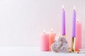 Heart and burning candles in pastel colors on white textured background. Royalty Free Stock Photo