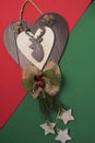 Heart carved in wood with reindeer and Christmas bow, decoration for the doors on a red and green background. Christmas season wit Royalty Free Stock Photo