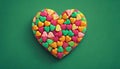 heart colored candies on green background