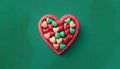 heart colored candies on green background