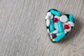 Heart from colorful medication and pills above on grey wooden background. Copy space. Top view, frame. Painkillers, tablets, gene Royalty Free Stock Photo