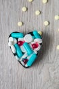 Heart from colorful medication and pills above on grey wooden background. Copy space. Top view, frame. Painkillers, tablets, gene