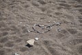 Heart with Cupid`s arrow is made of stones on the beach. Kolimpia, Rhodes, Greece