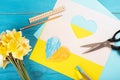 heart cut out of paper and painted in blue and yellow colors and yellow spring flowers on wooding back. Creativity Royalty Free Stock Photo