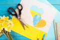 heart cut out of paper and painted in blue and yellow colors and yellow spring flowers on wooding back. Creativity Royalty Free Stock Photo