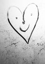 Heart with a drawn face with voices and smile on frosty glass in winter with a finger, heart emoticon drawing by February 14 on