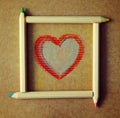 Heart drawn on paper in a frame from colored wooden pencils.