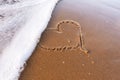 Heart drawn on the sand of the beach, soft sea wave. Love concept. Royalty Free Stock Photo