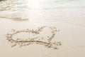 Heart drawn on a sand of beach with the wave of the sea in the bright sunlight. Royalty Free Stock Photo