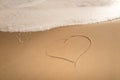 Heart drawn on a sand of beach with the wave of the sea Romantic love background Royalty Free Stock Photo