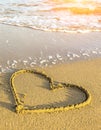 Heart drawn in sea beach sand, soft wave in a sunny day. Nature. Royalty Free Stock Photo