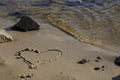 a heart is drawn on a wet sandy shore with stones on the beach by the river Royalty Free Stock Photo