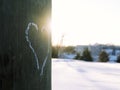 Heart drawn with white chalk on electric pole with sun shining and snow