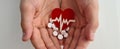 Heart electrocardiogram icon and white pills in children hands