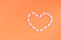 heart is exposed with white pills on a orange background. Medical concept.Flat Lay